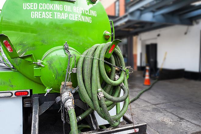 worker pumping grease trap at commercial kitchen in Greenport